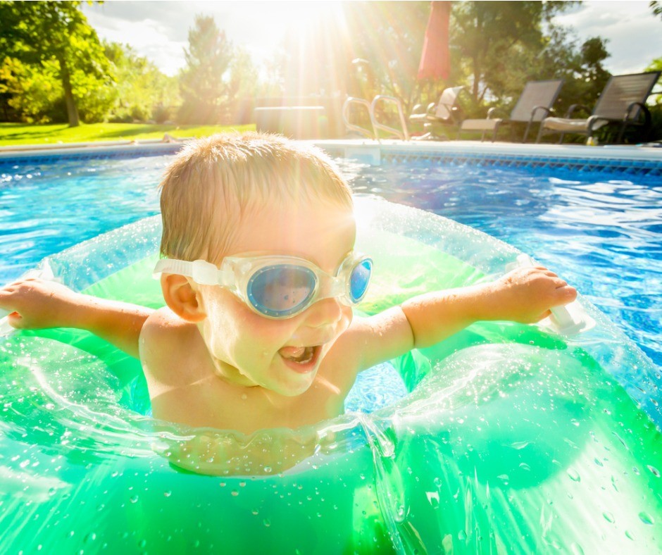 Young child wearing goggles in a swimming inside a water flotation toy.